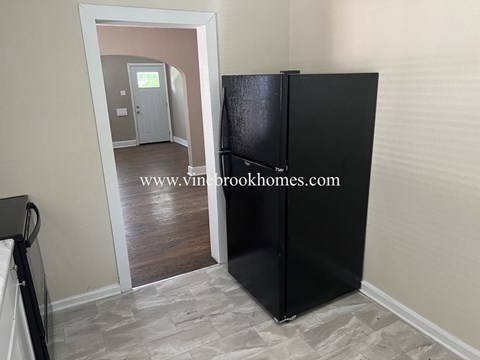 a kitchen with a refrigerator and a door to a hallway