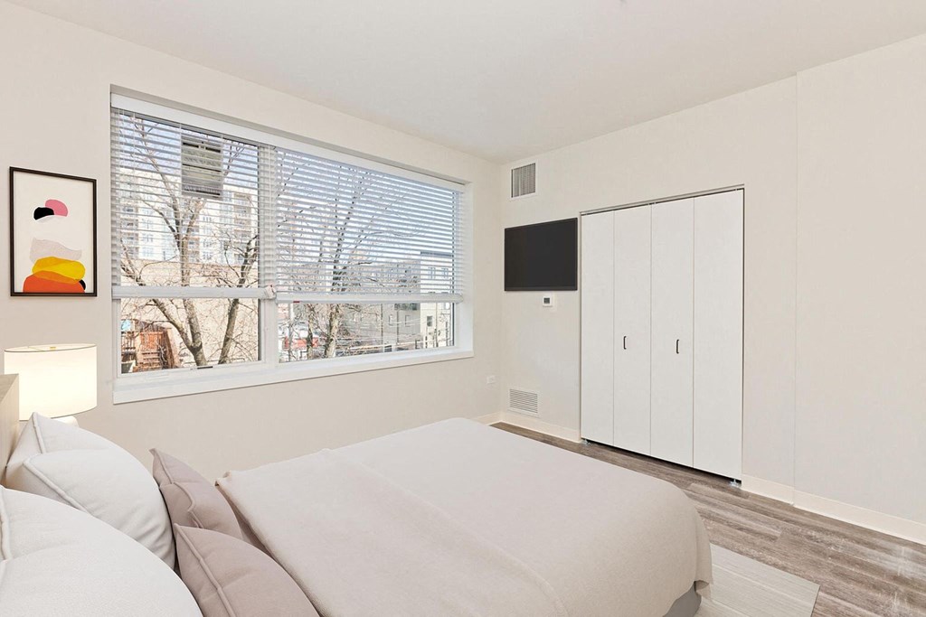 a bedroom with a bed and a large window