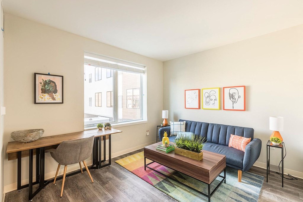 a living room with a couch and a desk and a window