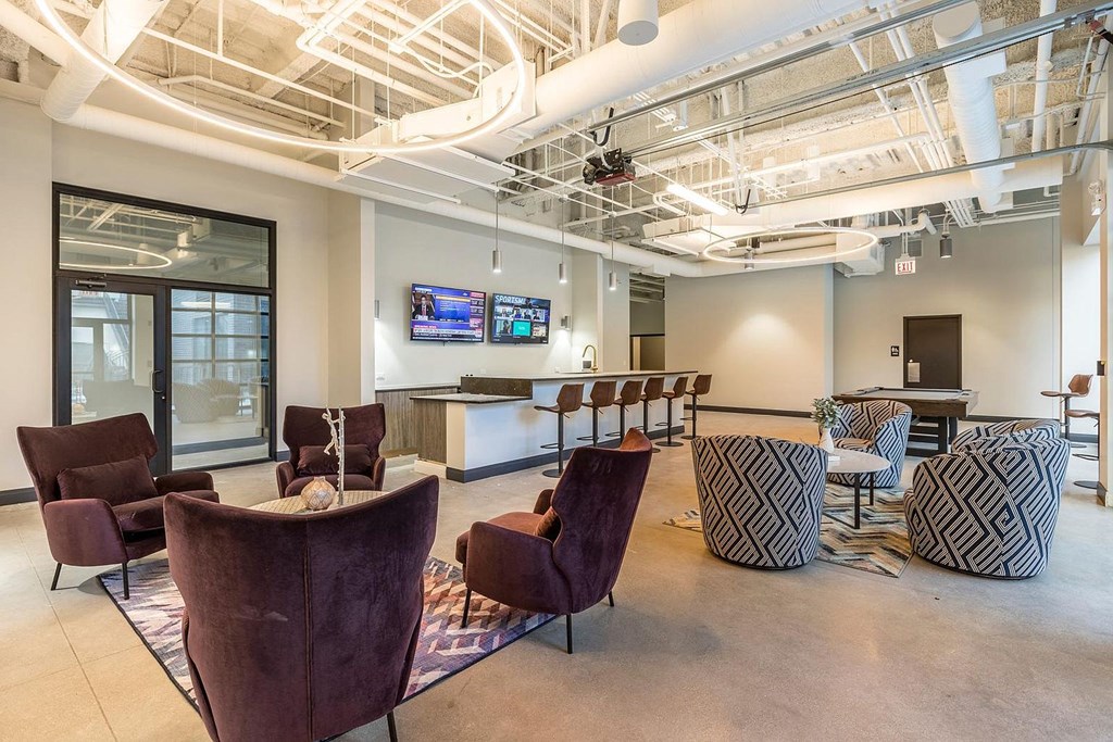 a lounge area with chairs and a bar and a tv