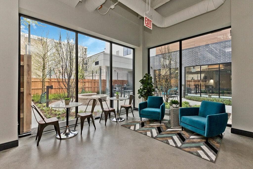 a lobby with chairs and tables and large windows