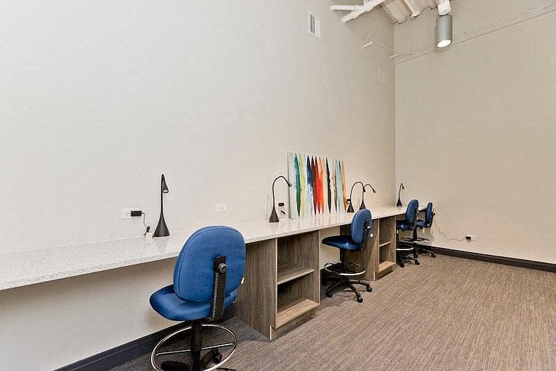 a room with a long desk with three chairs