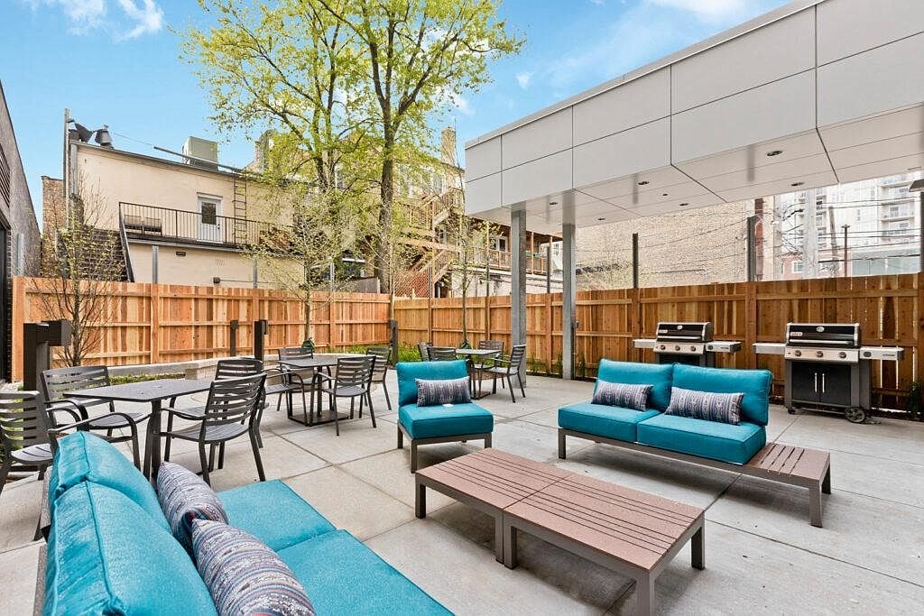 a patio with couches tables and chairs and a grill