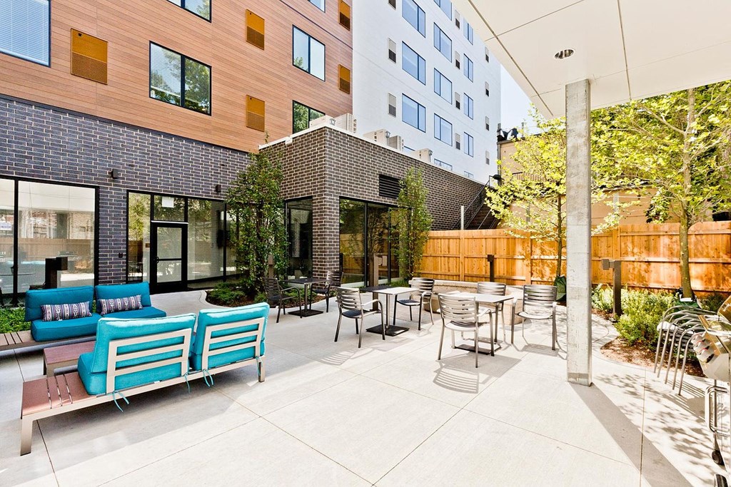 a patio with blue benches and tables in front of a building