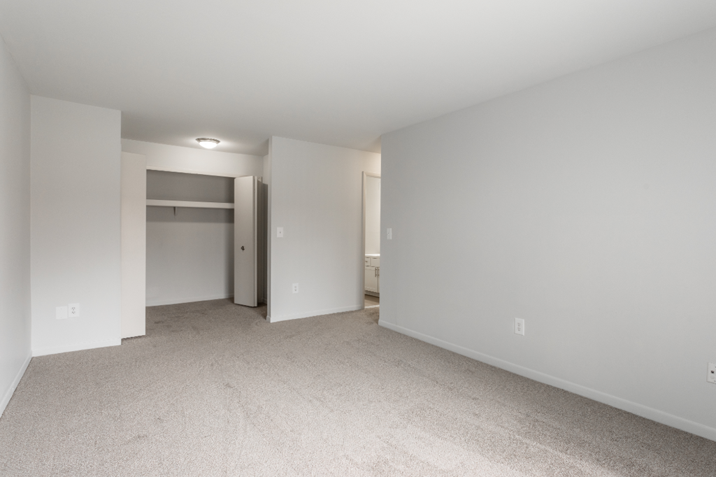 an empty living room with white walls and a closet