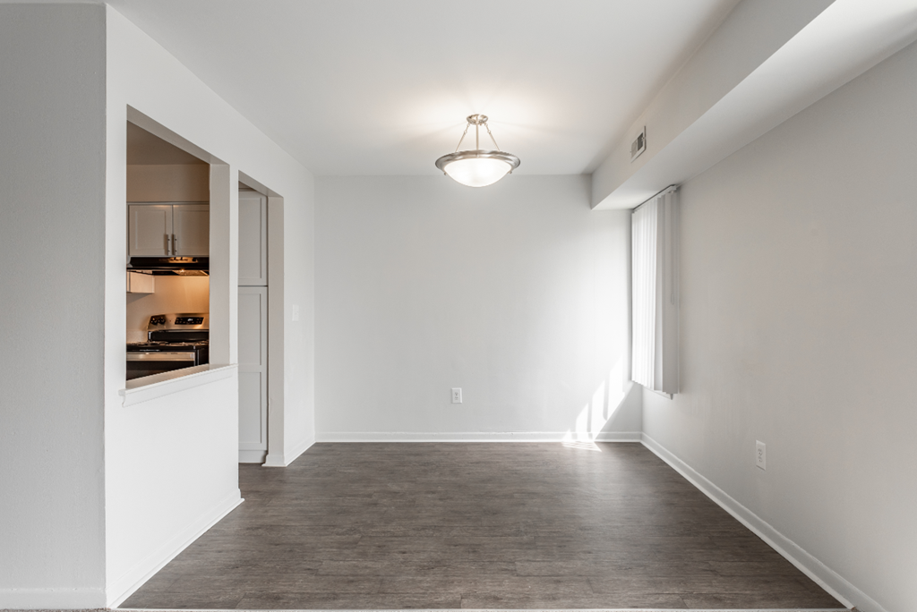an empty living room with white walls and a door to a kitchen