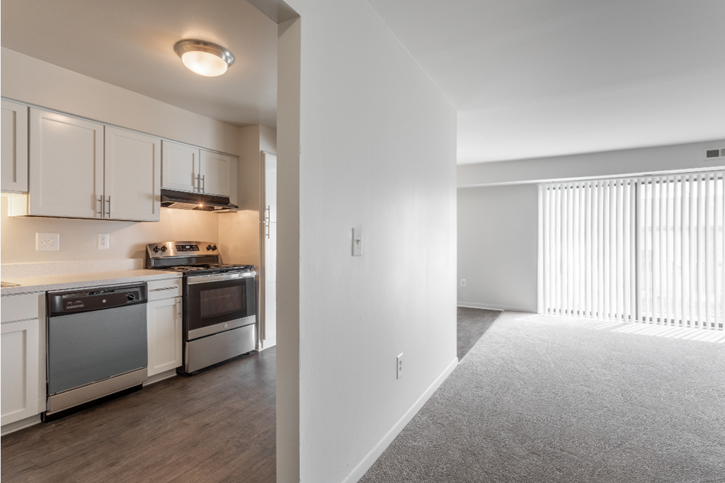 an empty kitchen with white cabinets and appliances and a large window