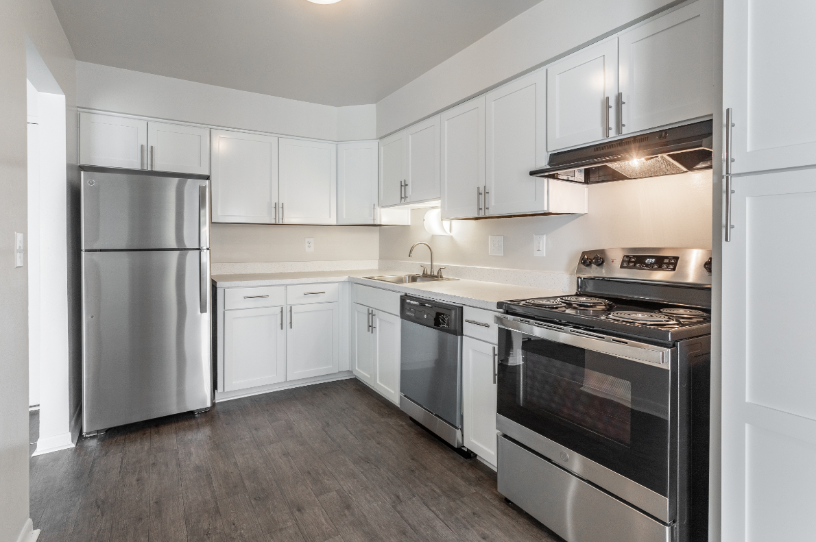 an empty kitchen with white cabinets and stainless steel appliances