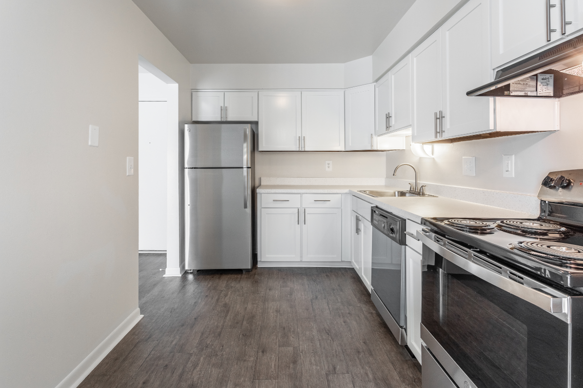 an empty kitchen with stainless steel appliances and white cabinets