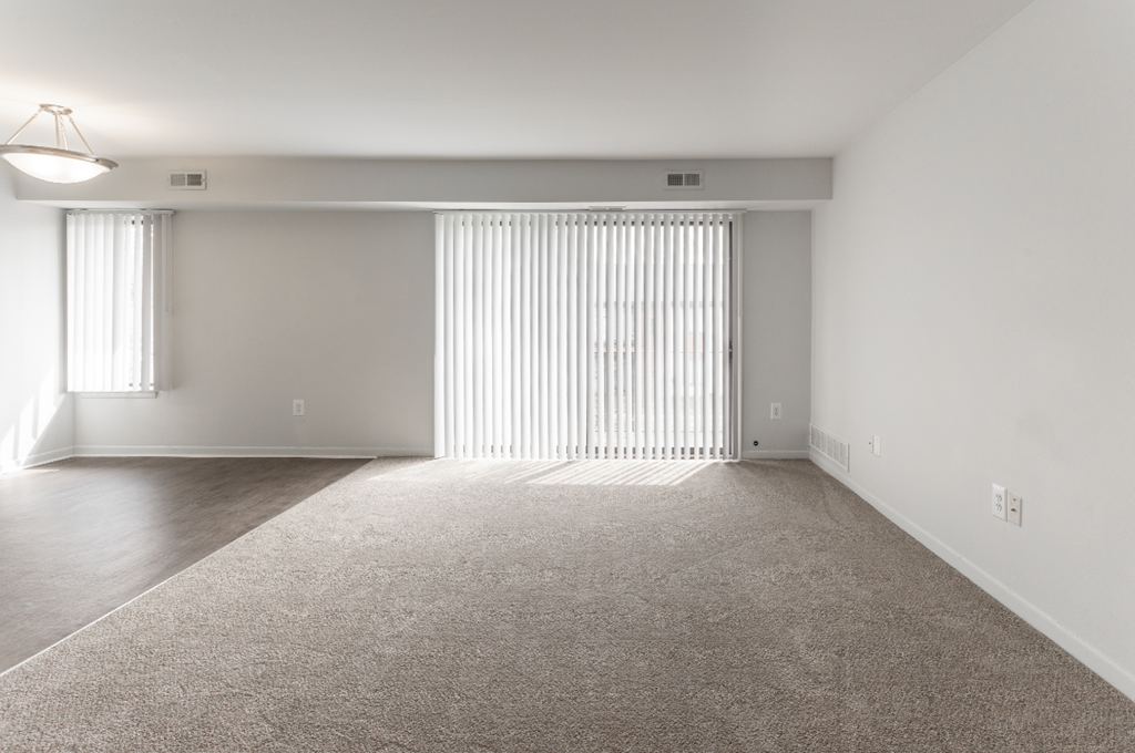 an empty living room with white walls and a window