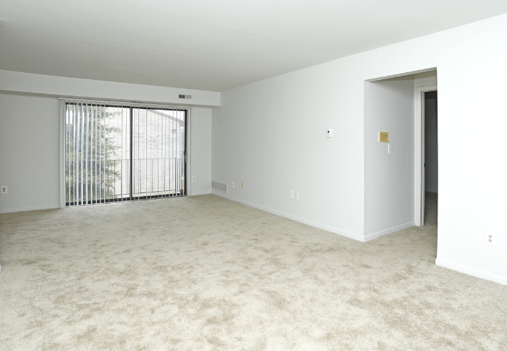 an empty living room with white walls and a window