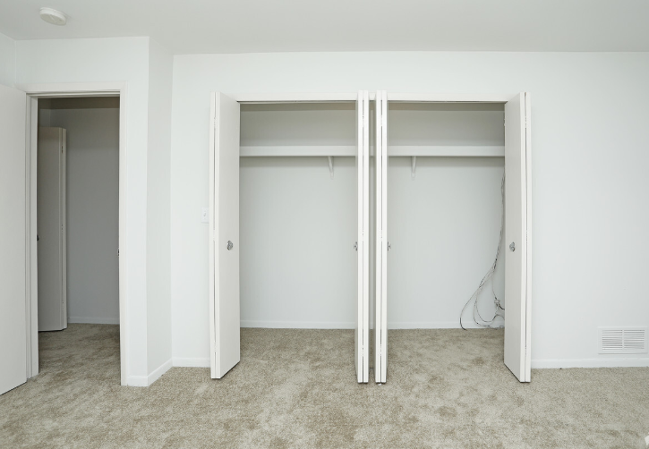 an empty bedroom with three closets and a carpeted floor