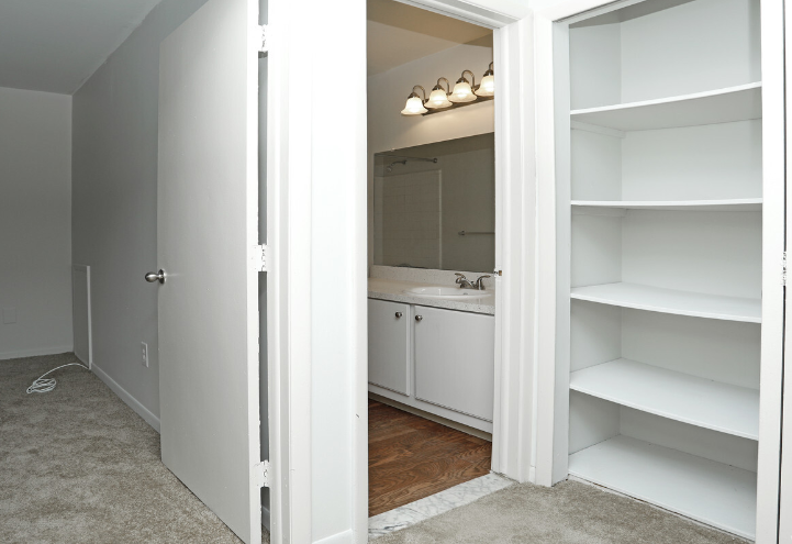 a closet with white shelves and a sink and a mirror