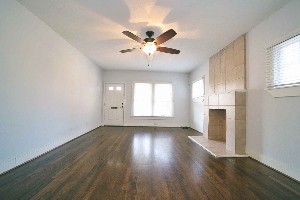 an empty living room with a ceiling fan