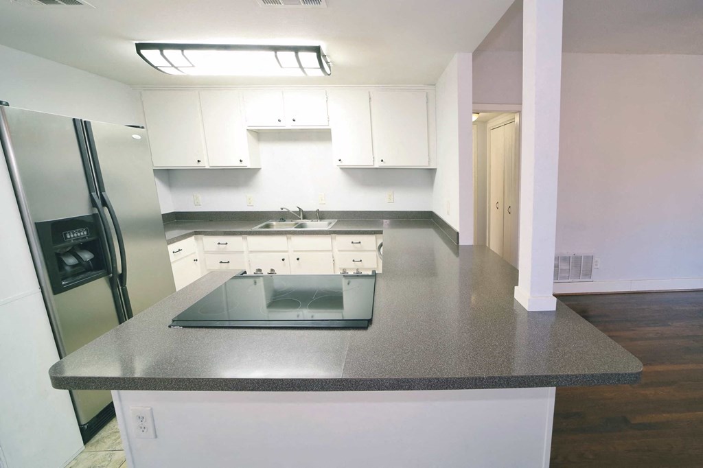 an empty kitchen with white cabinets and a counter top