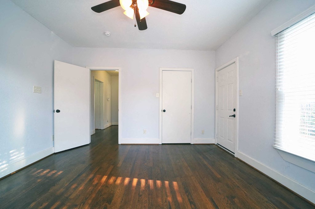 an empty living room with white walls and a ceiling fan