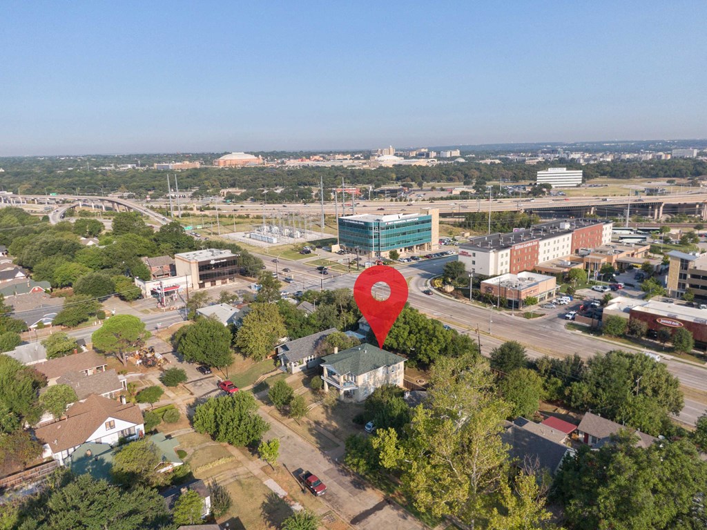 an aerial view of a city with a red arrow pinpointing a building with a