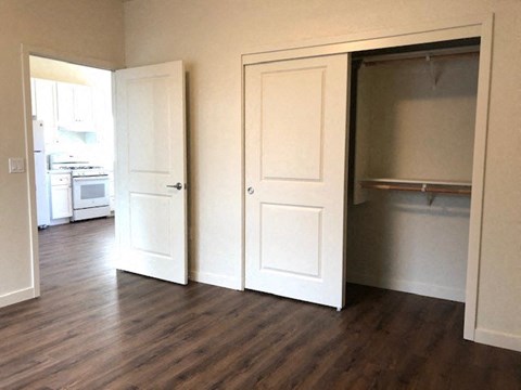 an empty living room with doors open to a kitchen
