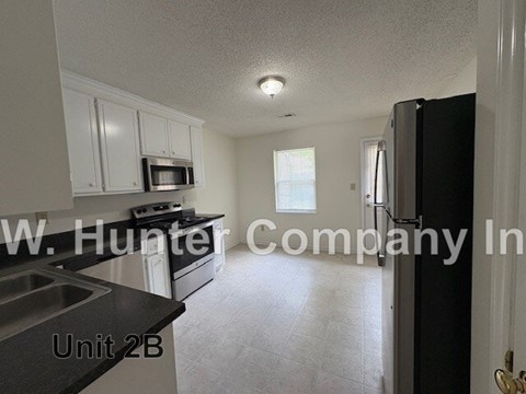 A kitchen with white cabinets and a black counter top.