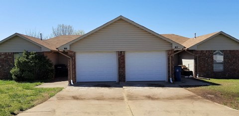 a house with two white garage doors and a driveway
