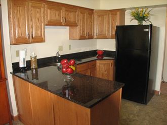 a kitchen with wooden cabinets and a black refrigerator