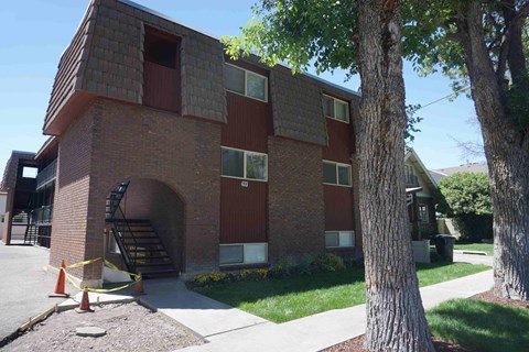 A red and brown building with a tree in front.