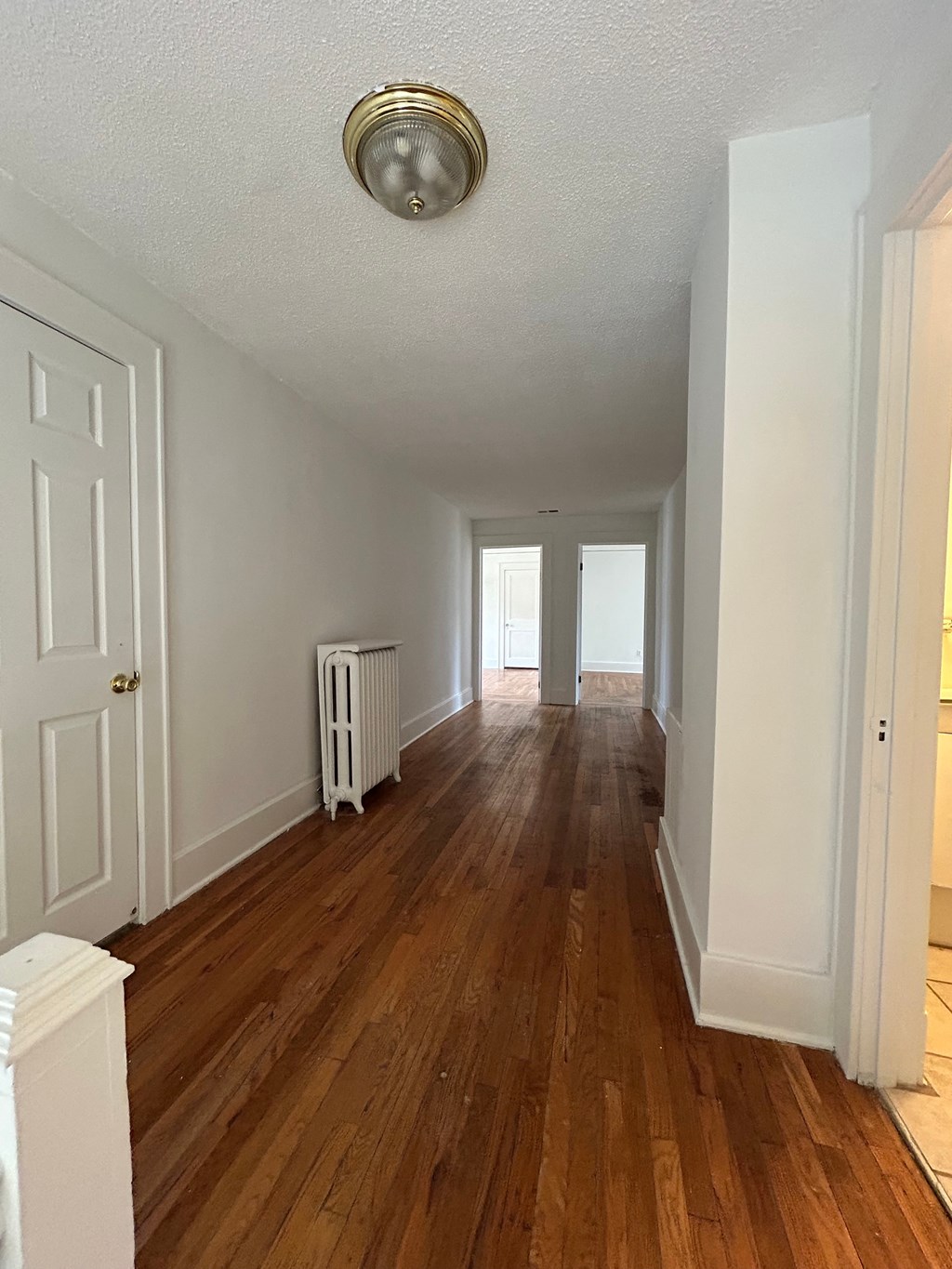 A long hallway with wood floors and white walls.
