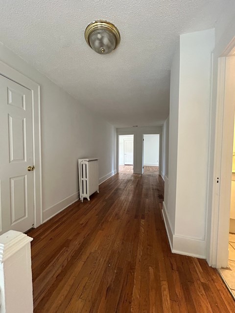 A long hallway with wood floors and white walls.