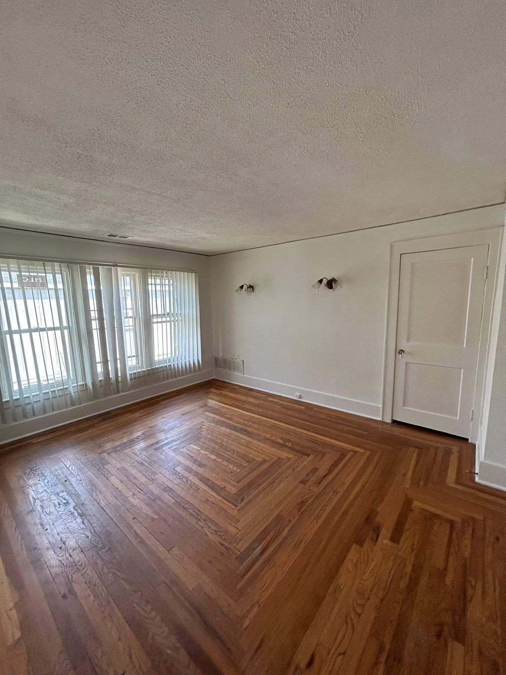 A room with wooden flooring and white walls.