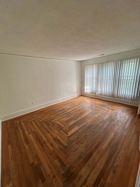 A room with wooden flooring and a window with blinds.