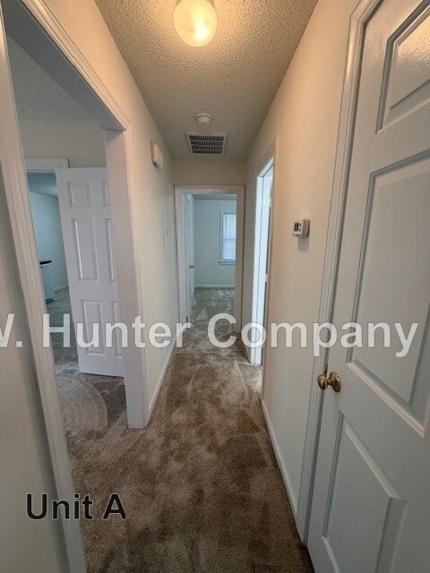 A hallway with a carpeted floor and white walls.