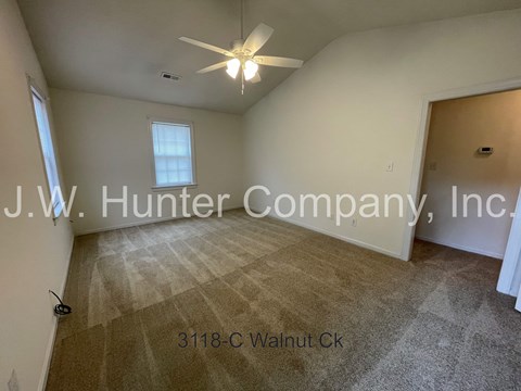 A room with a carpeted floor and a ceiling fan, with the text "J.W. Hunter Company, Inc." and an address "3118-C Walnut Ck" overlaid on the image.