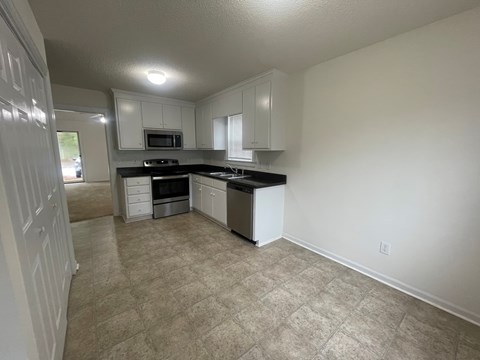 A kitchen with white cabinets and a black countertop.
