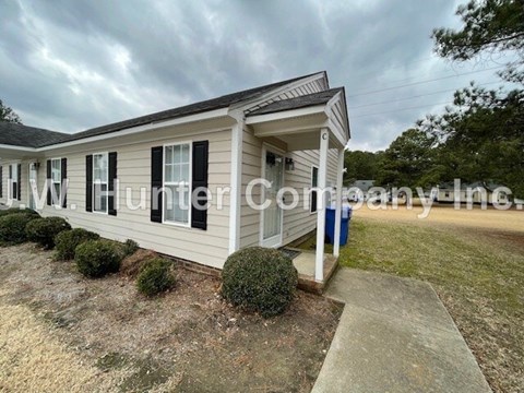 A mobile home with a white porch and black shutters.