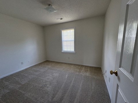 A room with a carpeted floor and a door on the right side.
