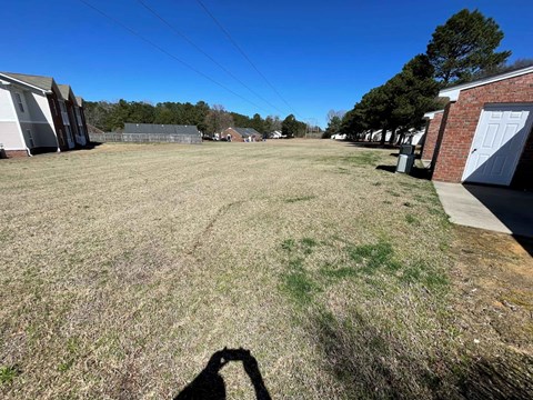 A shadow of a person holding a camera is cast on a grassy field.