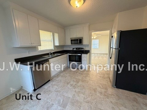 A kitchen with black countertops and white cabinets is labeled Unit C.