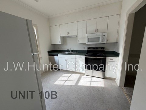 A kitchen with white cabinets and appliances in a unit labeled 10B.