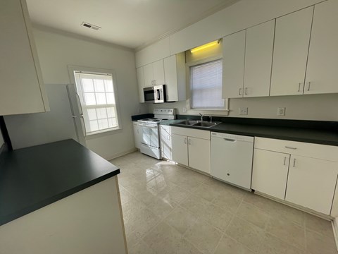 A kitchen with white cabinets and black countertops.