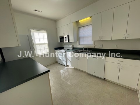 A kitchen with white cabinets and a black countertop.