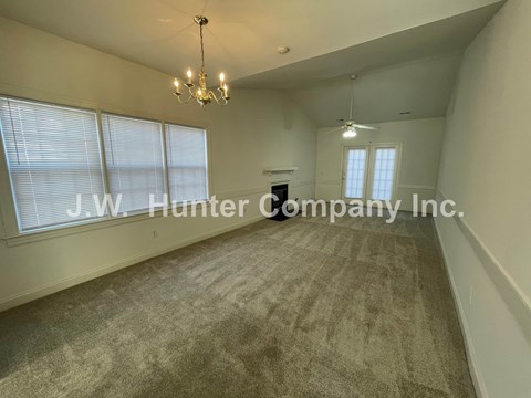A spacious room with a carpeted floor and a chandelier hanging from the ceiling.