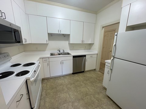 A kitchen with white cabinets and appliances.
