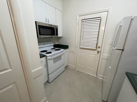 A small kitchen with a white oven and microwave.