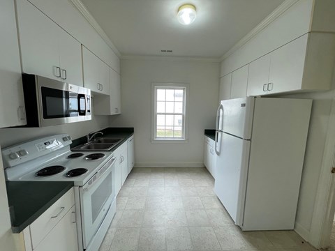 A kitchen with white cabinets and a black countertop.