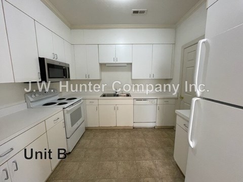 A kitchen with white cabinets and appliances in a small room.