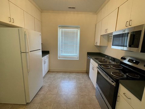 A kitchen with white cabinets and black countertops.