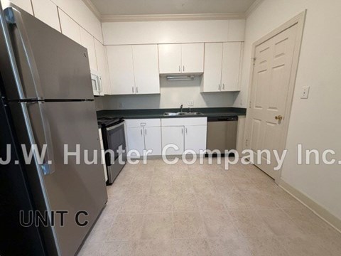 A kitchen with white cabinets and a black countertop.