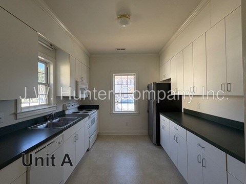 A kitchen with white cabinets and black countertops.