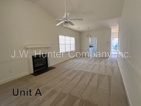 A spacious living room with a carpet floor and a ceiling fan.