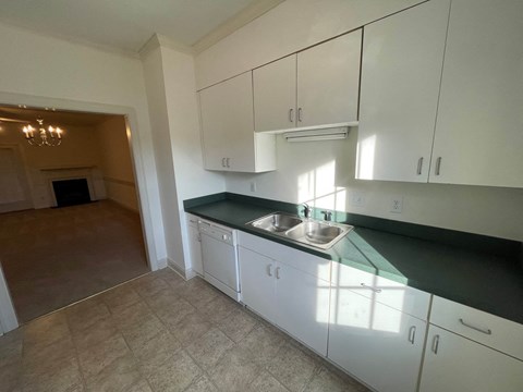 A kitchen with white cabinets and a green countertop.